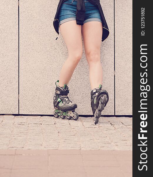 woman slim legs wearing roller skates standing outside. Sport activity concept. woman slim legs wearing roller skates standing outside. Sport activity concept.