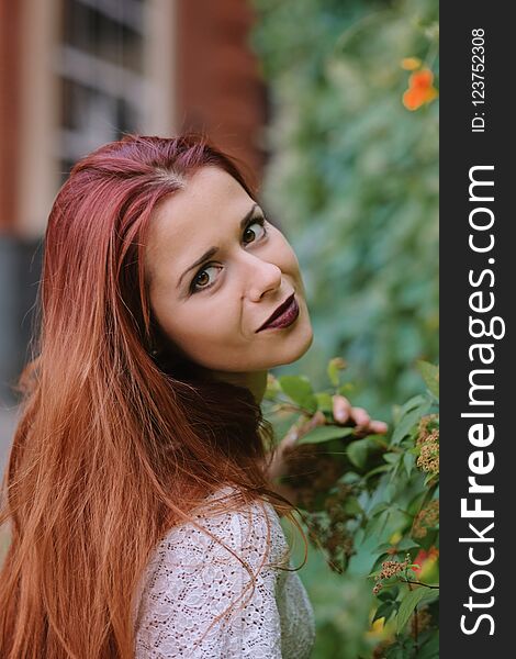 Fashion art photo. Portrait of woman with long red hair, in the city.