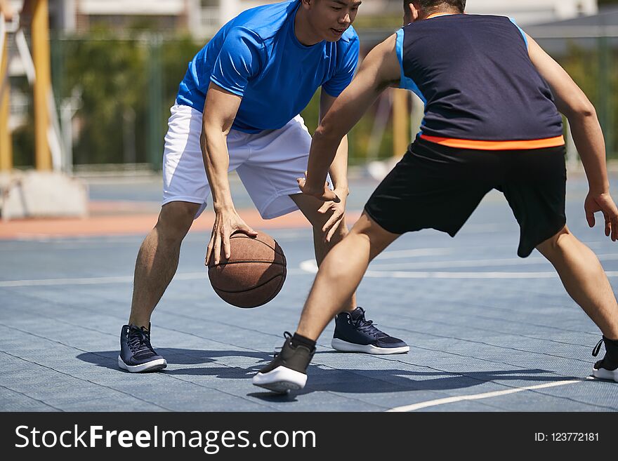 Young asian adult players playing basketball on outdoor court. Young asian adult players playing basketball on outdoor court.