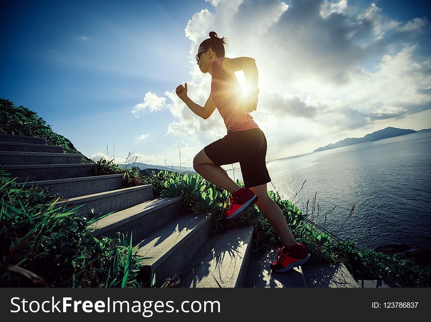 Woman running up on seaside mountain stairs