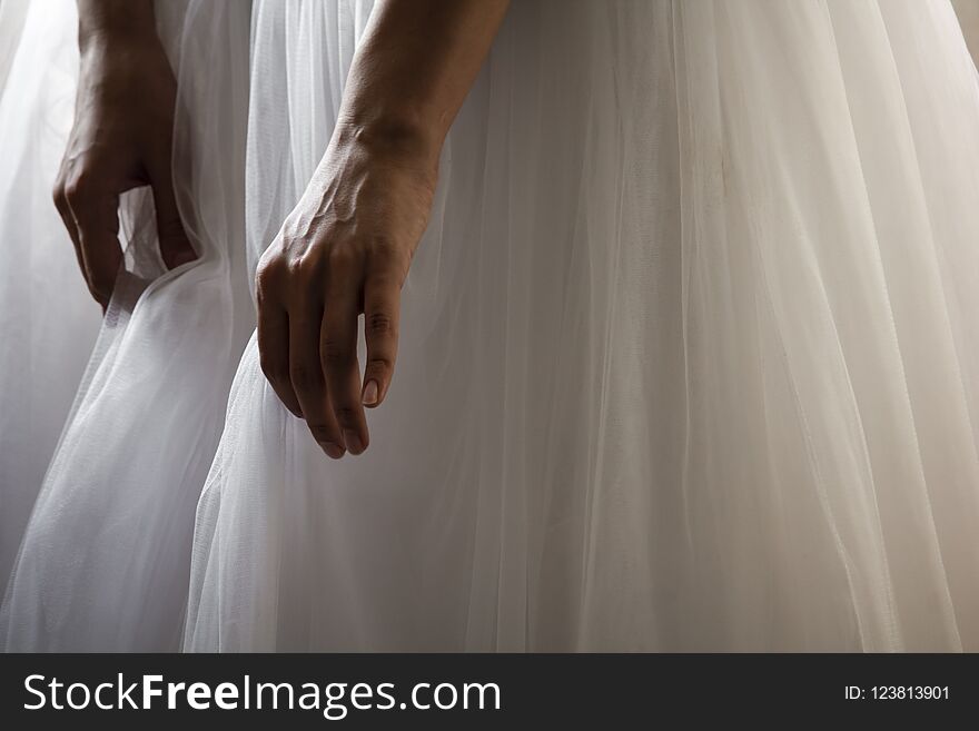 A bride in a beautiful wedding dress holding her dress hem