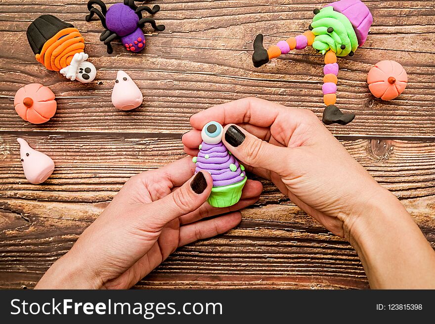 Female hands with black nails making halloween cupcake craft on wooden table top view