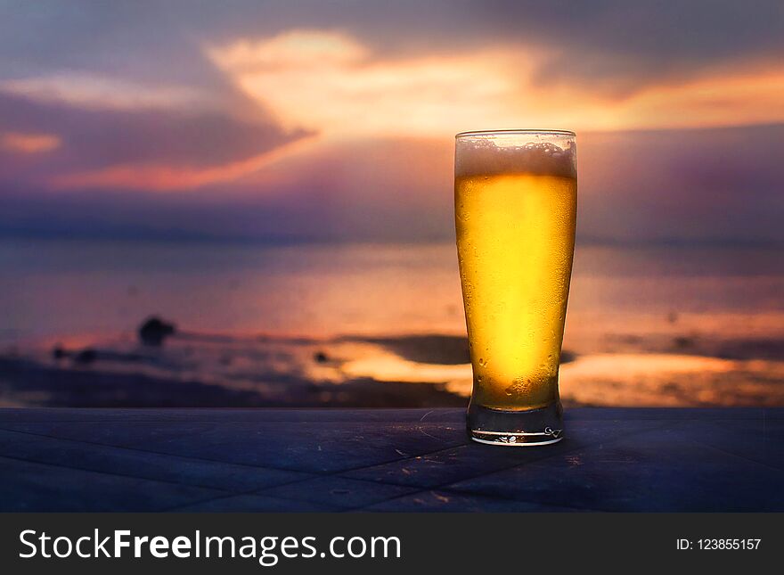 Beer in glass on the beach in sunset. Beer in glass on the beach in sunset