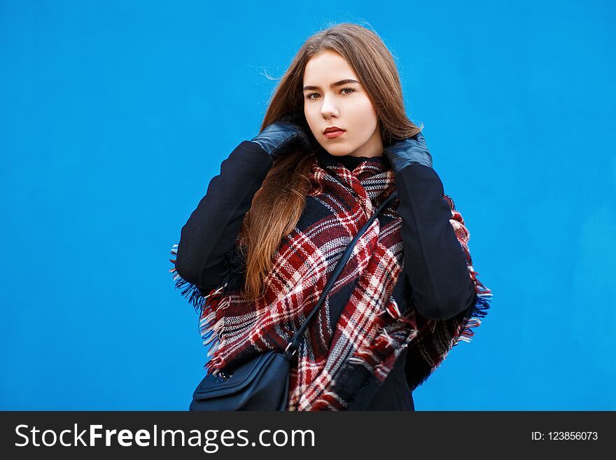 Beautiful Woman With A Scarf And Coat Posing Near A Bright Blue