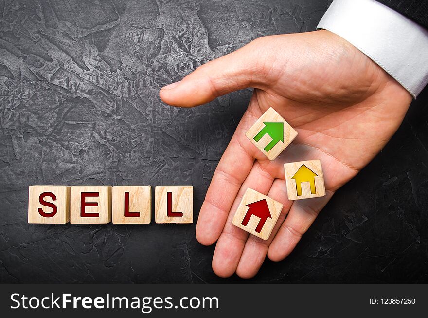 The hand of the realtor puts a cube with a picture of the house to the word sale. Concept of selling a house, apartment, real estate. The market of immobility. Trade of property. Affordable housing.