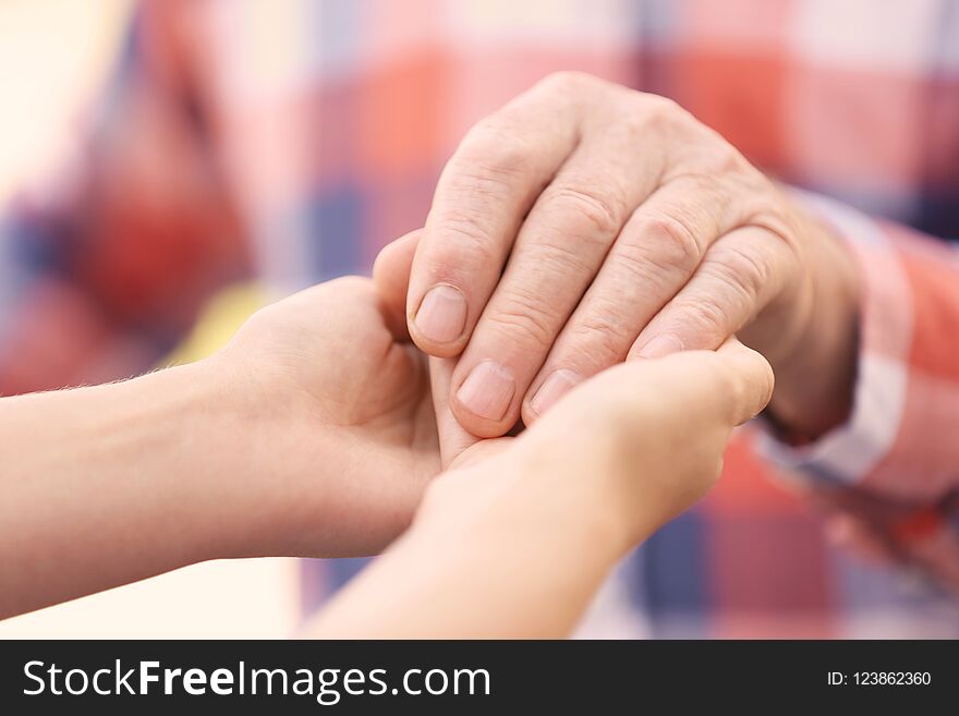 Young woman holding elderly man hand, closeup. Help service