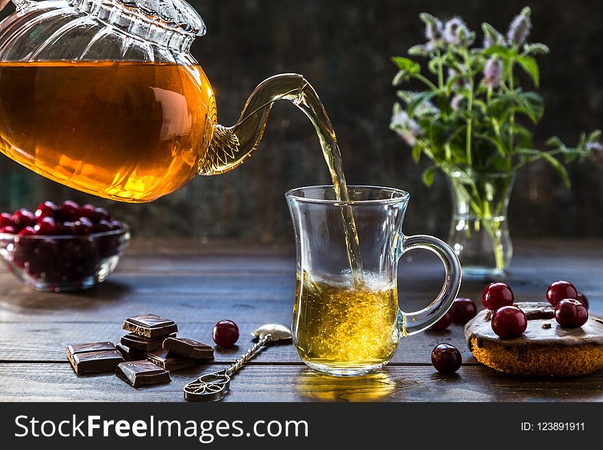 Hot tea pours from a transparent teapot into a glass. Hot tea pours from a transparent teapot into a glass.