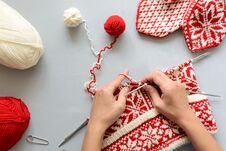 Girl Knits Red And White Norwegian Jacquard Hat Knitting Needles On Gray Wooden Background Royalty Free Stock Photography