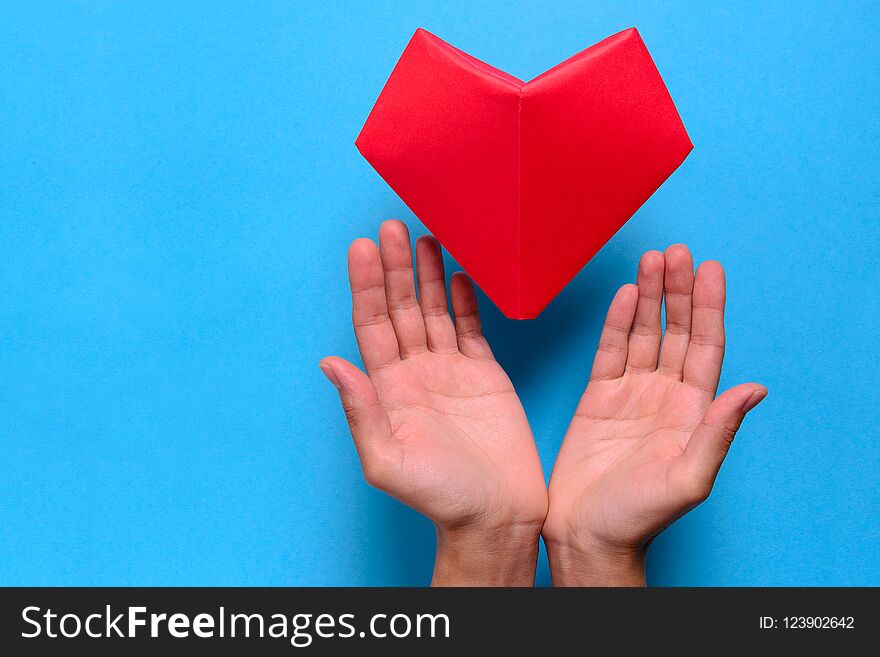 Heart health or Valentine`s day concept. Hands holding red paper heart. Origami.