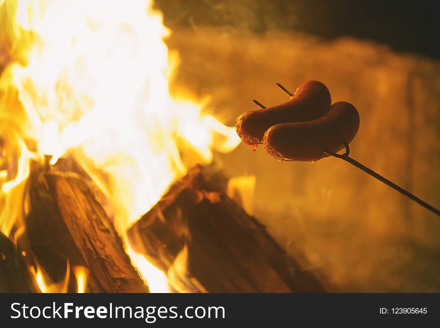 Roasting sausages on the fire. Summer picnic or camping concept. Roasting sausages on the fire. Summer picnic or camping concept