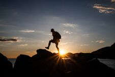 Man Jumping On Cliffs In Sunset Stock Image