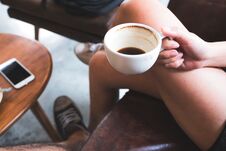 A Woman Holding Black Coffee Cup While Sitting On Sofa With Friend In Cafe Stock Photo