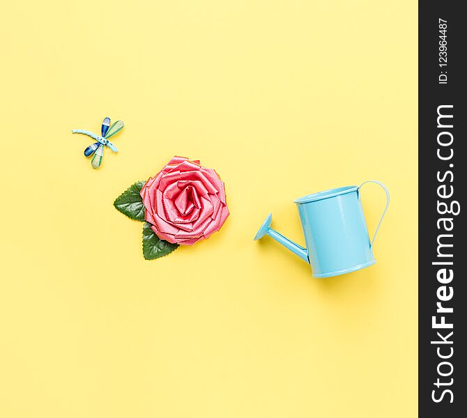 Watering can, rose flower and dragonfly. Minimal concept mock up. Flat lay
