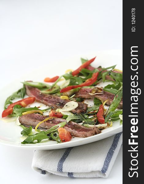 Finely sliced raw bleu beef with rocket and baby capsicum. Reduced depth of field with washout background. Focus on the salad. Angled view with layout space. Finely sliced raw bleu beef with rocket and baby capsicum. Reduced depth of field with washout background. Focus on the salad. Angled view with layout space.