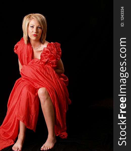 Young model wrapped in red against a black backdrop. Young model wrapped in red against a black backdrop.