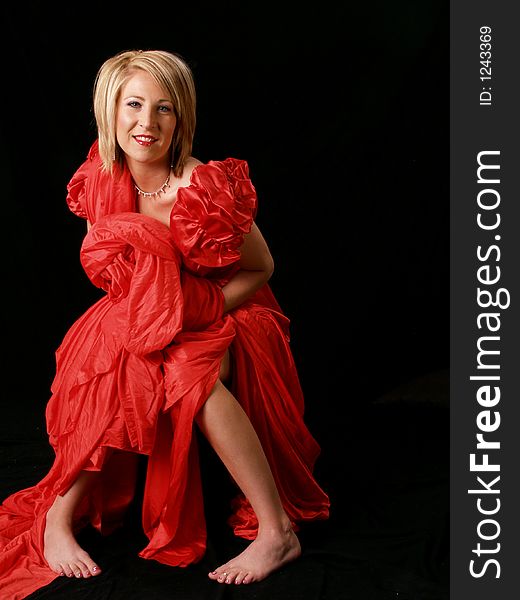 Young model wrapped in red against a black backdrop. Young model wrapped in red against a black backdrop.