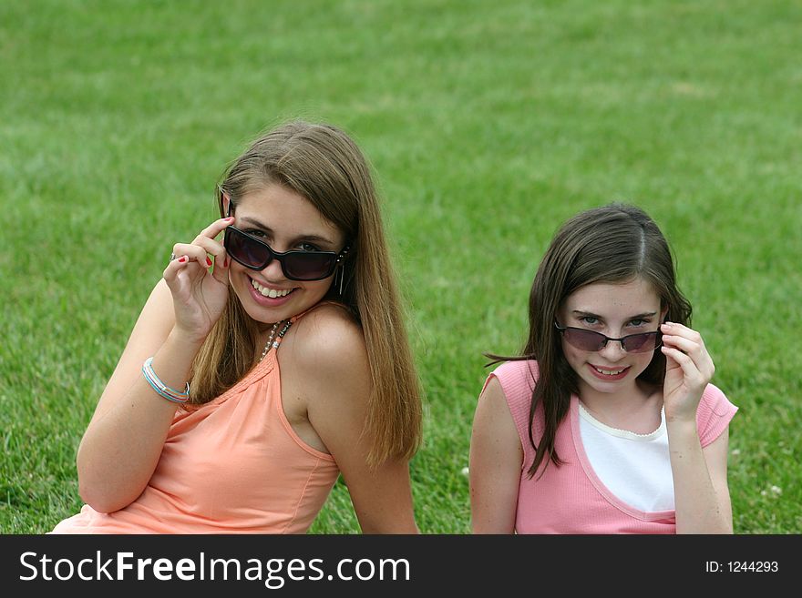 Two girls pulling down sunglasses. Two girls pulling down sunglasses