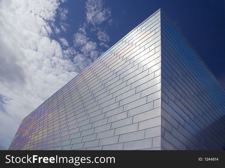 The face of a modern titanium-clad building against a blue sky. The face of a modern titanium-clad building against a blue sky