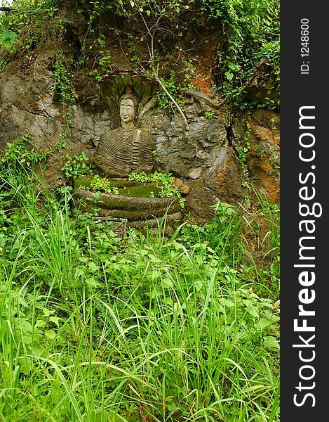 Old buddha statue against a rock on a mountainside.