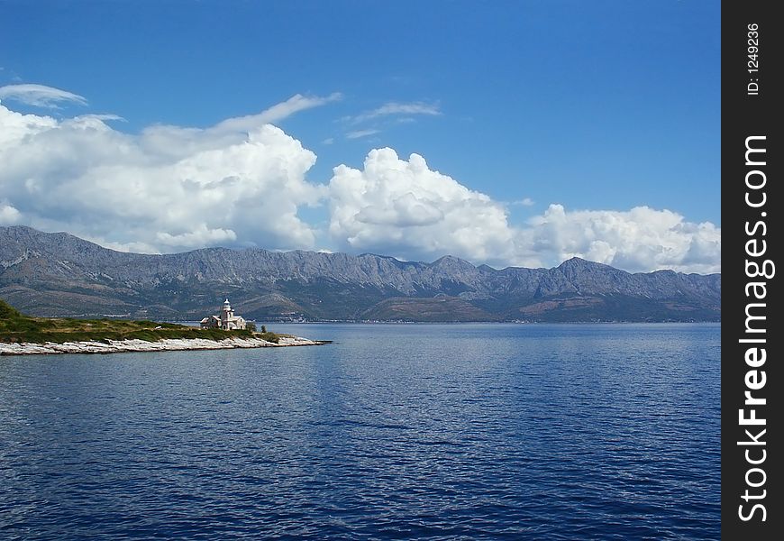 Lighthouse in blue adriatic sea under Biokovo mountain in south Adria, Croatia