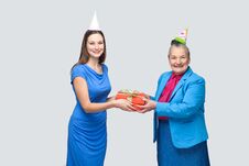 Young Woman Gives A Gift To Old Funny Woman For Birthday Royalty Free Stock Photo