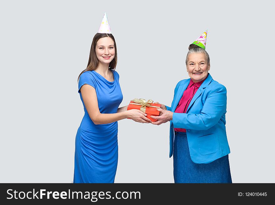 Young woman gives a gift to old funny woman for birthday
