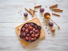 Dessert Of Baked Plum In A Pan With Cloves, Cinnamon, Honey And Zest. Stock Photo