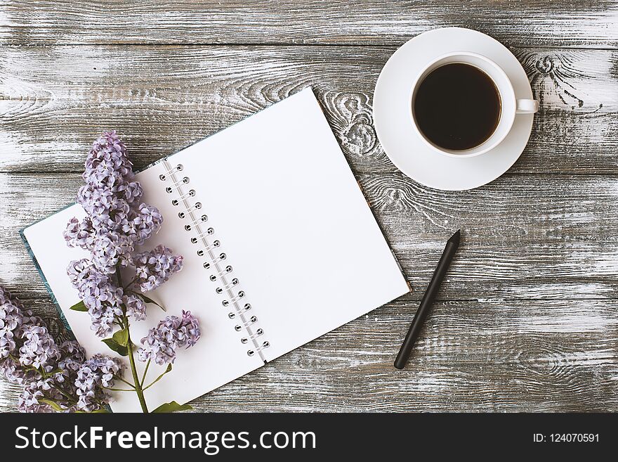Top view of a diary or notebook, pencil and coffee and a purple flower on a gray wooden table. Flat design.