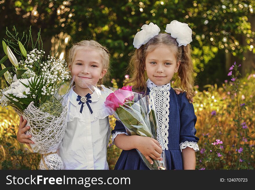 Two happy little schoolgirls with the flowers. Two happy little schoolgirls with the flowers