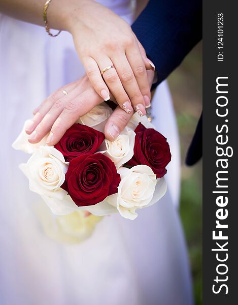 Wedding bouquet of red and white roses in the hands of the bride and groom at the wedding in the summer. Wedding bouquet of red and white roses in the hands of the bride and groom at the wedding in the summer