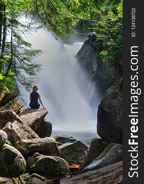 Woman Near Waterfalls Sitting On Rocks.