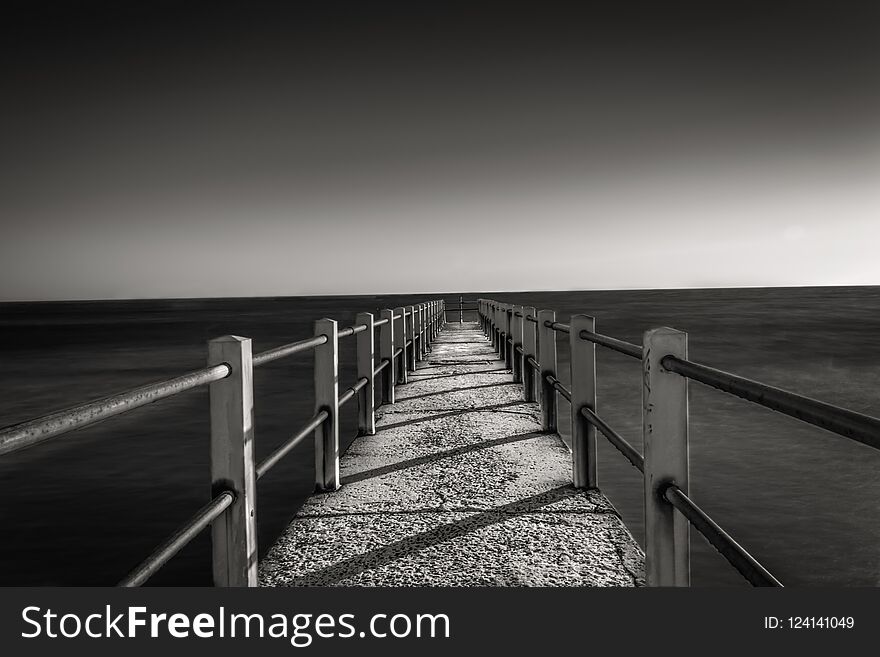 Black and white photo of jetty at sunset