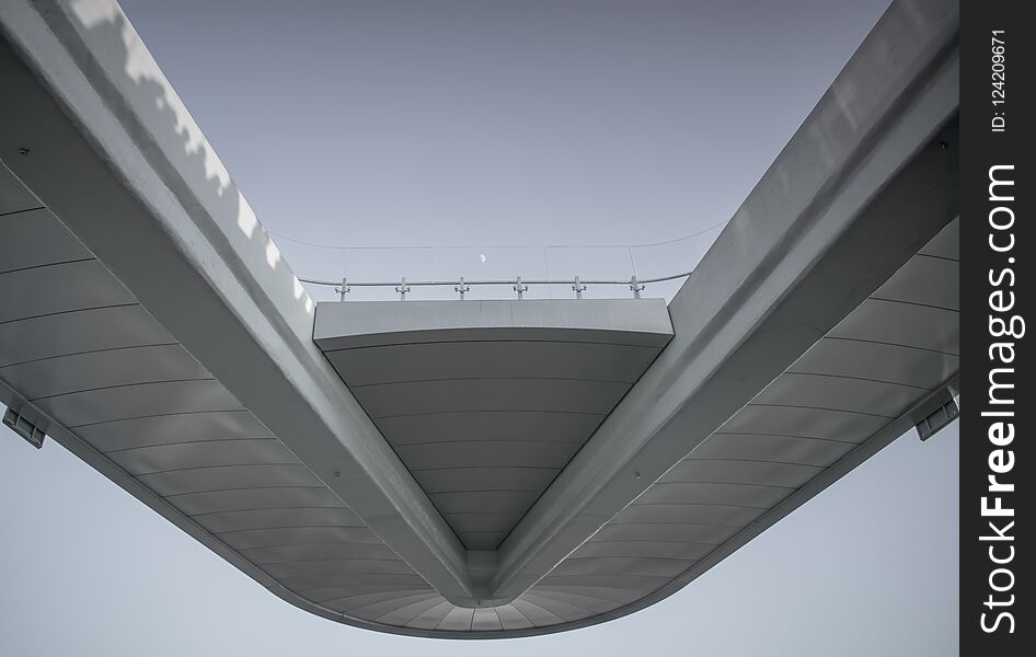 White bridge with transparent fence on sky background and small hardly noticeable moon. Footpath in the sky. Pedestrian bridge in Moscow Zaryadye Park near red square and the Kremlin. Under the bridge