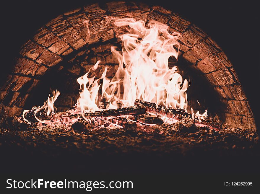 Close up. Fire in the oven. Pizza in the coals. Dark background. Concepts of cooking on a fire in the oven. mate color