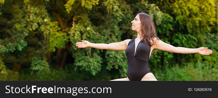 Slim young woman practicing yoga in nature. Virabhadrasana pose.