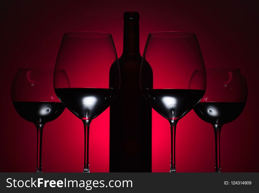 Glasses and bottle of red wine on a red background. Glasses and bottle of red wine on a red background.