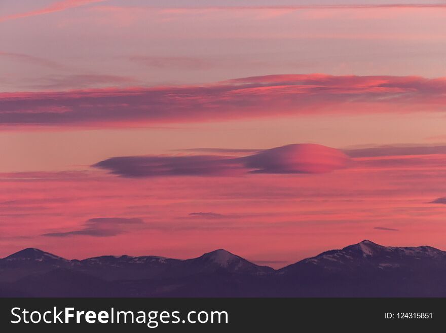 A view of some mountains top, beneath a beautiful, warm colored sky at sunset