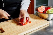 The Chef In The Cafe Cuts Tomatoes On A Wooden Kitchen Board Stock Image