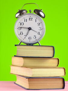 Alarm Clock On Top Of Piles Of Books On Yellow Background. Royalty Free Stock Images