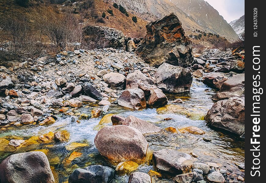 Mountain peak range landscape. Mountain meadow with mossy piled stones and small river in springtime as natural background.