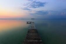 An Old Pier Reveals Views Of The Charmed Lake, Blue Sky With Cloud. Sunrise Enlightens The Horizon With Orange Warm Colors. Stock Photography An Old Pier Reveals Views Of The Charmed Lake, Blue Sky With Cloud. Sunrise Enlightens The Horizon With Orange Warm Colors. Stock Photography