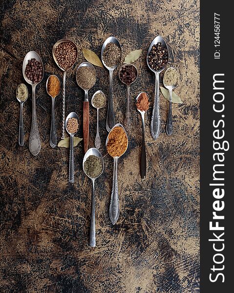 Different spices in spoons on a vintage background.