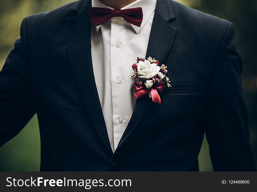 Groom or groomsmen closeup, bow tie and boutonniere on suit, con