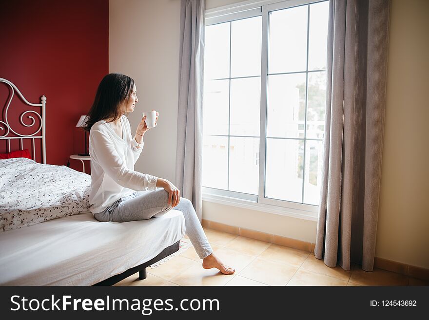 Beautiful girl in bed drinking coffee in morning