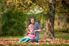 Mother And Girl Having Fun Under Tree With Autumn Leaves In The Park, Blond Cute Curly Girl, Happy And Young Family Royalty Free Stock Photography Mother And Girl Having Fun Under Tree With Autumn Leaves In The Park, Blond Cute Curly Girl, Happy And Young Family Royalty Free Stock Photography