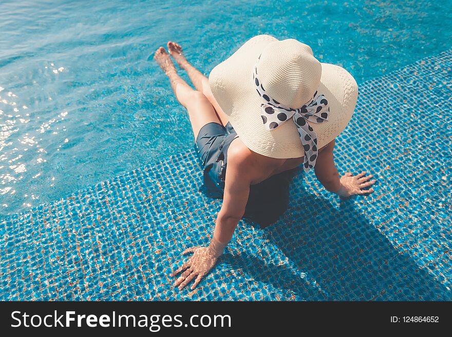 Portrait of asian woman relaxing in swimming pool with sunbathe.