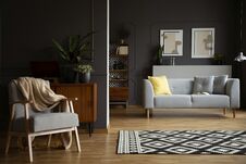 Blanket On Armchair Next To Patterned Carpet In Living Room Interior With Grey Sofa. Real Photo Stock Photo Blanket On Armchair Next To Patterned Carpet In Living Room Interior With Grey Sofa. Real Photo Stock Photo