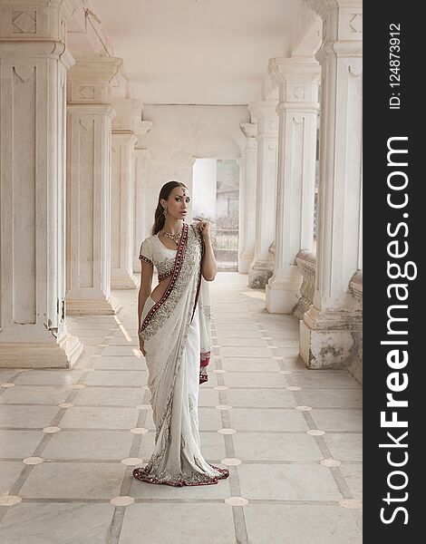 Beautiful young Indian Woman in Traditional Clothing with Bridal Makeup and Oriental Jewelry. Girl dancer in Sari posing outdoor near the Eastern Palace. Eastern fairy tale