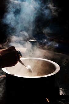 Woman`s Hand With Rings Mixing Something Mystical In A Pot With Vapor On The Dark Background Stock Photo Woman`s Hand With Rings Mixing Something Mystical In A Pot With Vapor On The Dark Background Stock Photo