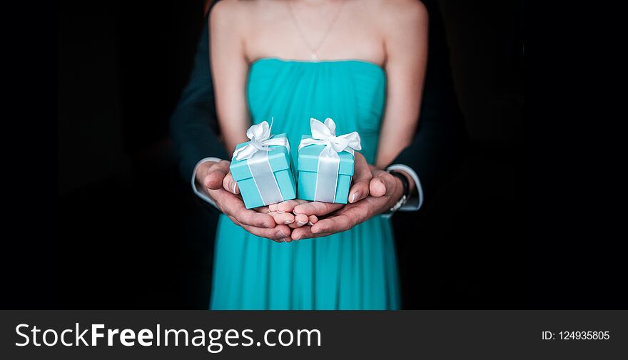 Guy with girl holding wedding gift in hands and showing in frame on the black bockground